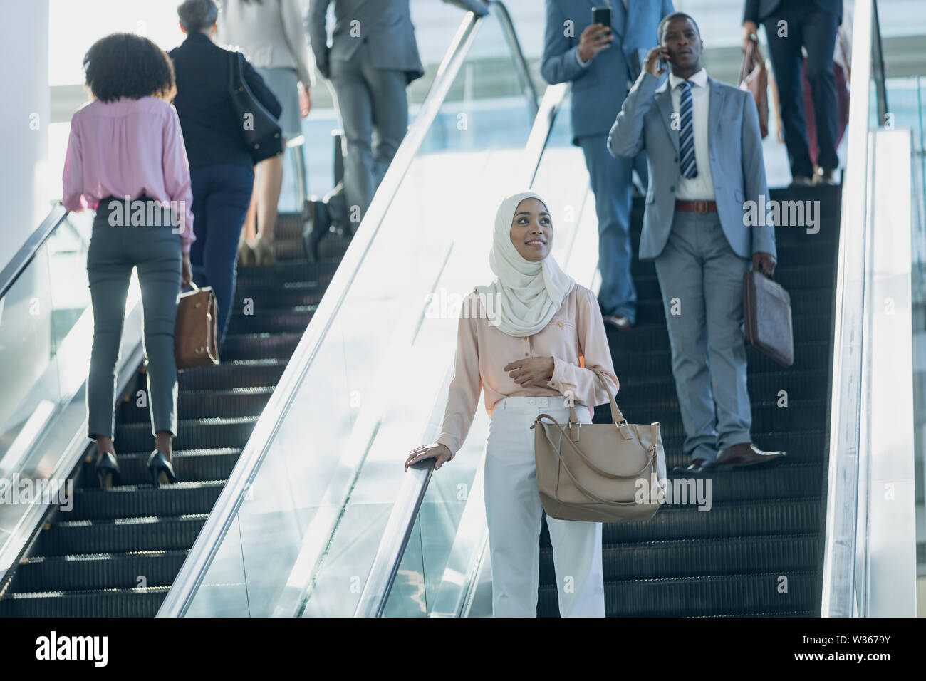 Diverse business people using escalators in modern office Stock Photo