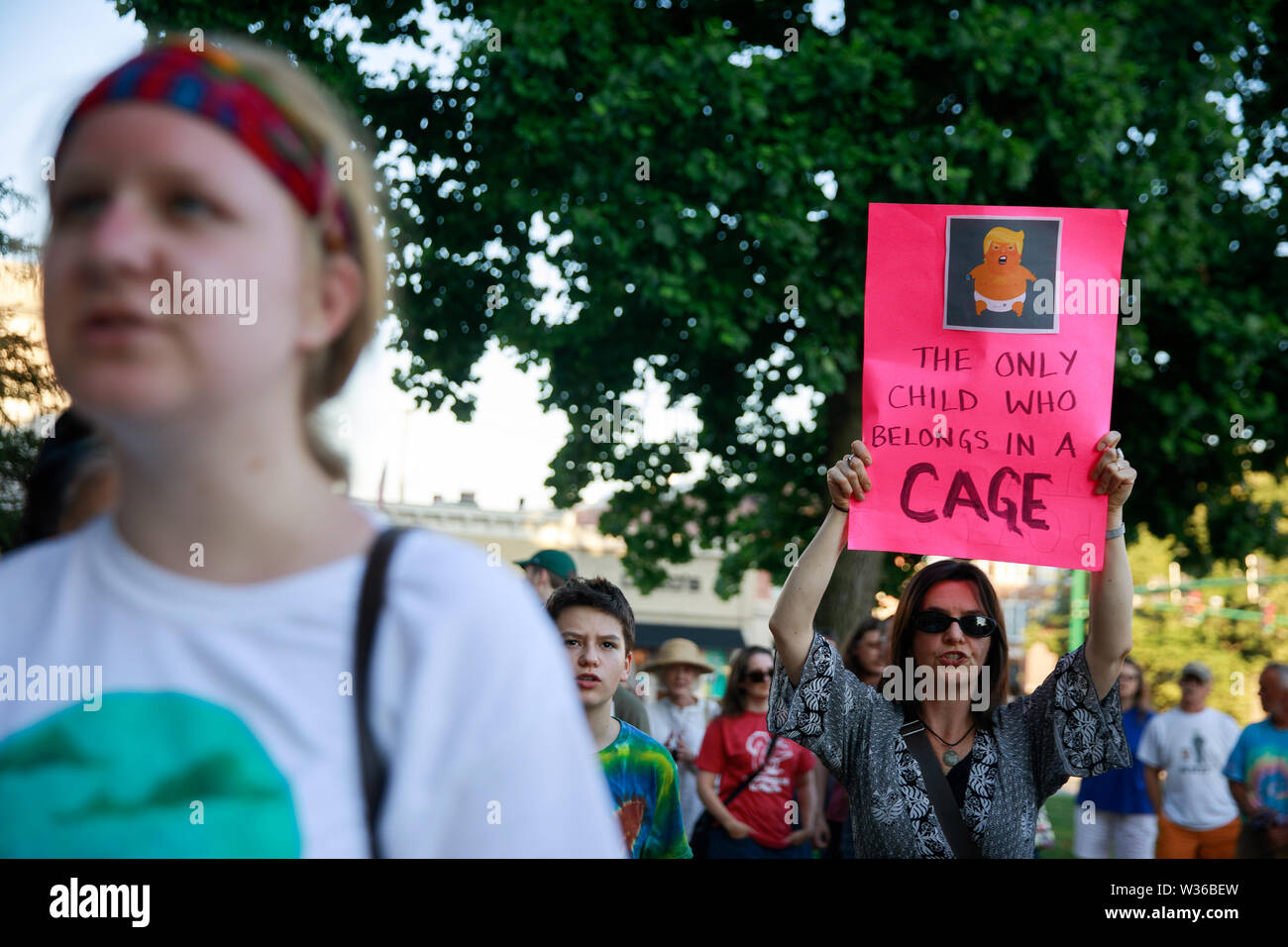 Bloomington, USA. 12th July, 2019. A woman holds a sign with a photo of 'Baby Trump,' reading, 'The Only Child Who Belongs in a Cage,' as protesters gather for the Lights for Liberty: A Vigil to End Human Detention Camps rally and candlelight vigil on the steps of the Monroe County Courthouse in Bloomington. USA President Donald J. Trump says ICE will conduct raids against undocumented immigrants in American cities over the weekend. Credit: SOPA Images Limited/Alamy Live News Stock Photo