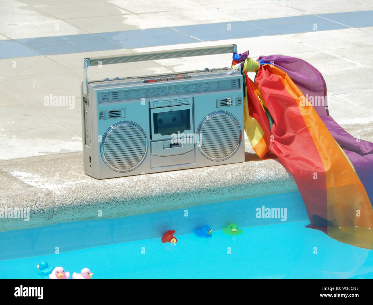 A large old radio at the edge of the pool with an LGTB flag and rubber
