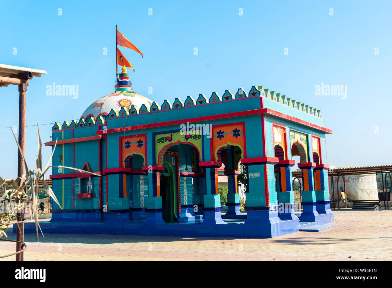 Small hindu temple with carvings in vivid blue and reds shot in gujarat india Stock Photo