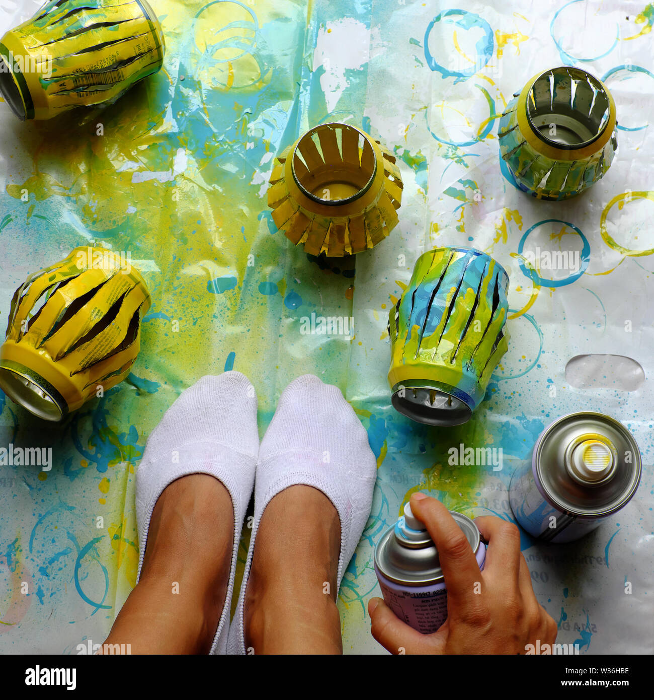Woman feet in white socks and group of colorful handmade lanterns recycling from beer cans, a home activity at free time in summer day Stock Photo