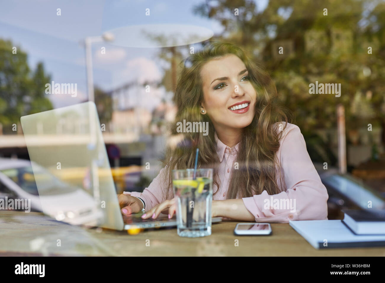 Attractive young woman working on laptop from cafe Stock Photo - Alamy