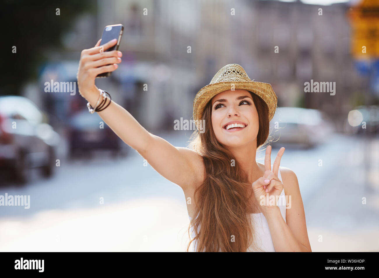 Happy young woman taking selfie with peace sign on city street Stock ...
