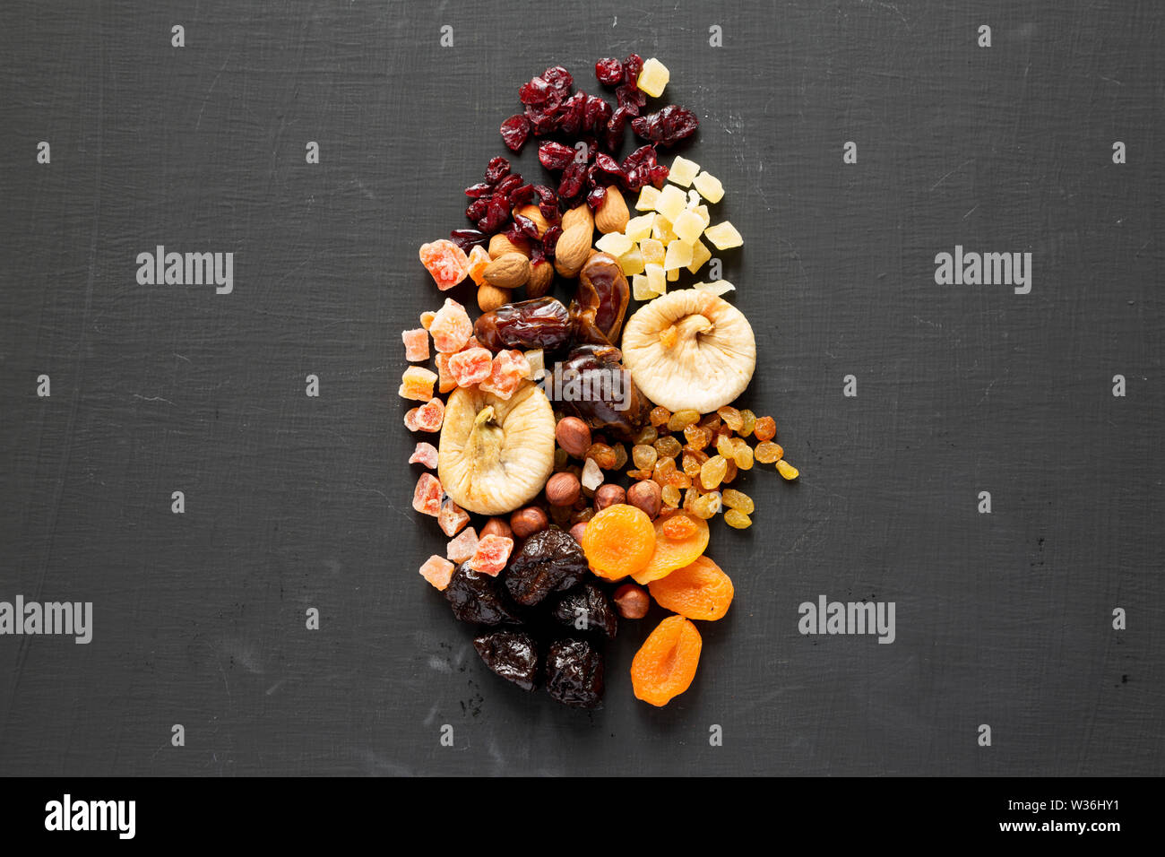 Dried fruits and nut mix on a black surface, top view. Overhead, flat