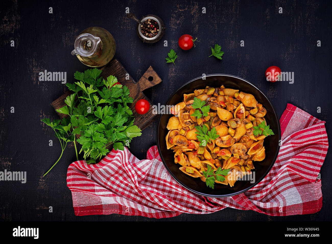 Conchiglie pasta. Italian pasta shells with mushrooms, zucchini and tomato sauce.  Top view Stock Photo