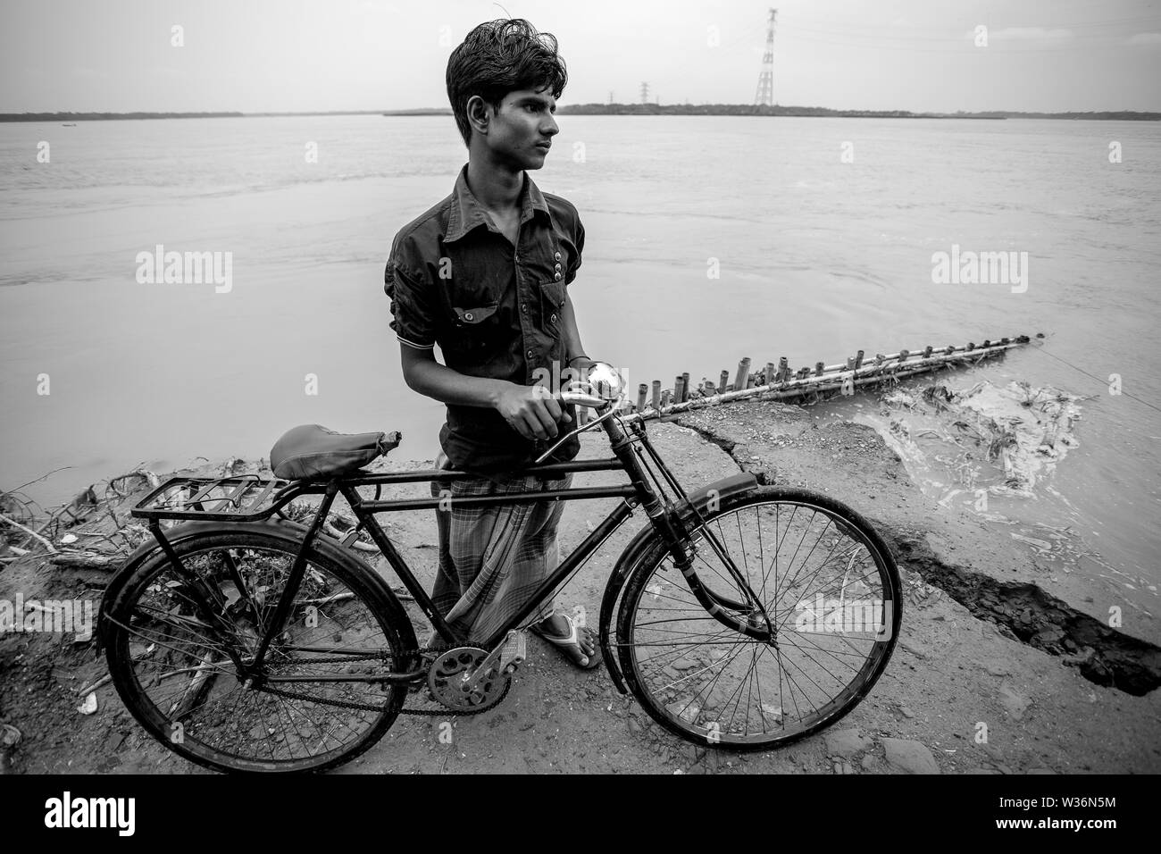 Bangladesh – June 27, 2015: A bicycle boy are stuck on the way due to river erosion at Rasulpur, Barisal District. Stock Photo