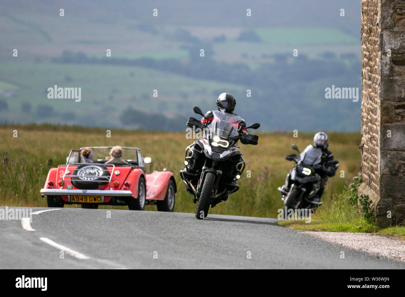 Morgan Plus 8 and motorbikes at Scorton, Lancashire, UK..  UK Weather 13th July, 2019.Sunny conditions as the Lancashire Car Club Rally Coast to Coast crosses the Trough of Bowland. 74 vintage, classic oldtimers, collectible, heritage, historics vehicles left Morecambe heading for a cross county journey over the Lancashire landscape to Whitby. A 170 mile trek over undulating landscape as part of the car club annual event. Credit: MediaWorldImages/Alamy Live News Stock Photo