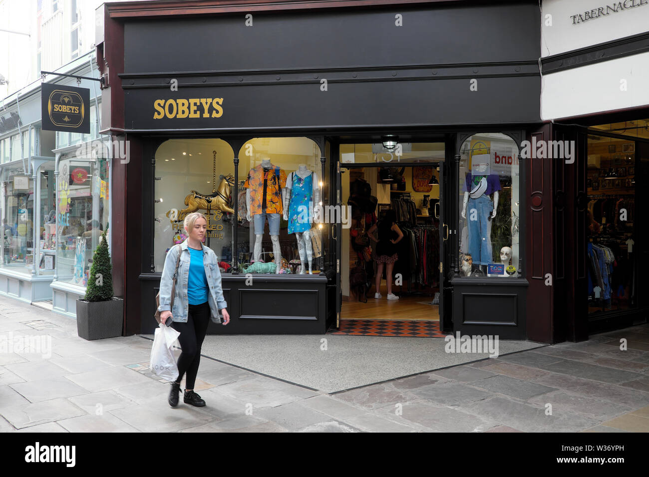 Exterior view of young woman walking past the entrance to Sobeys vintage clothing store in Royal Arcade Cardiff Wales UK  KATHY DEWITT Stock Photo
