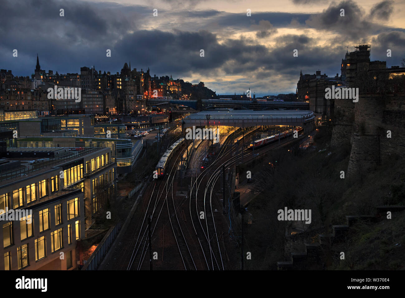 A Abellio Scotrail class 380 train arriving at Edinburgh Waverley stations east end at sunset with the Edinburgh skyline Stock Photo