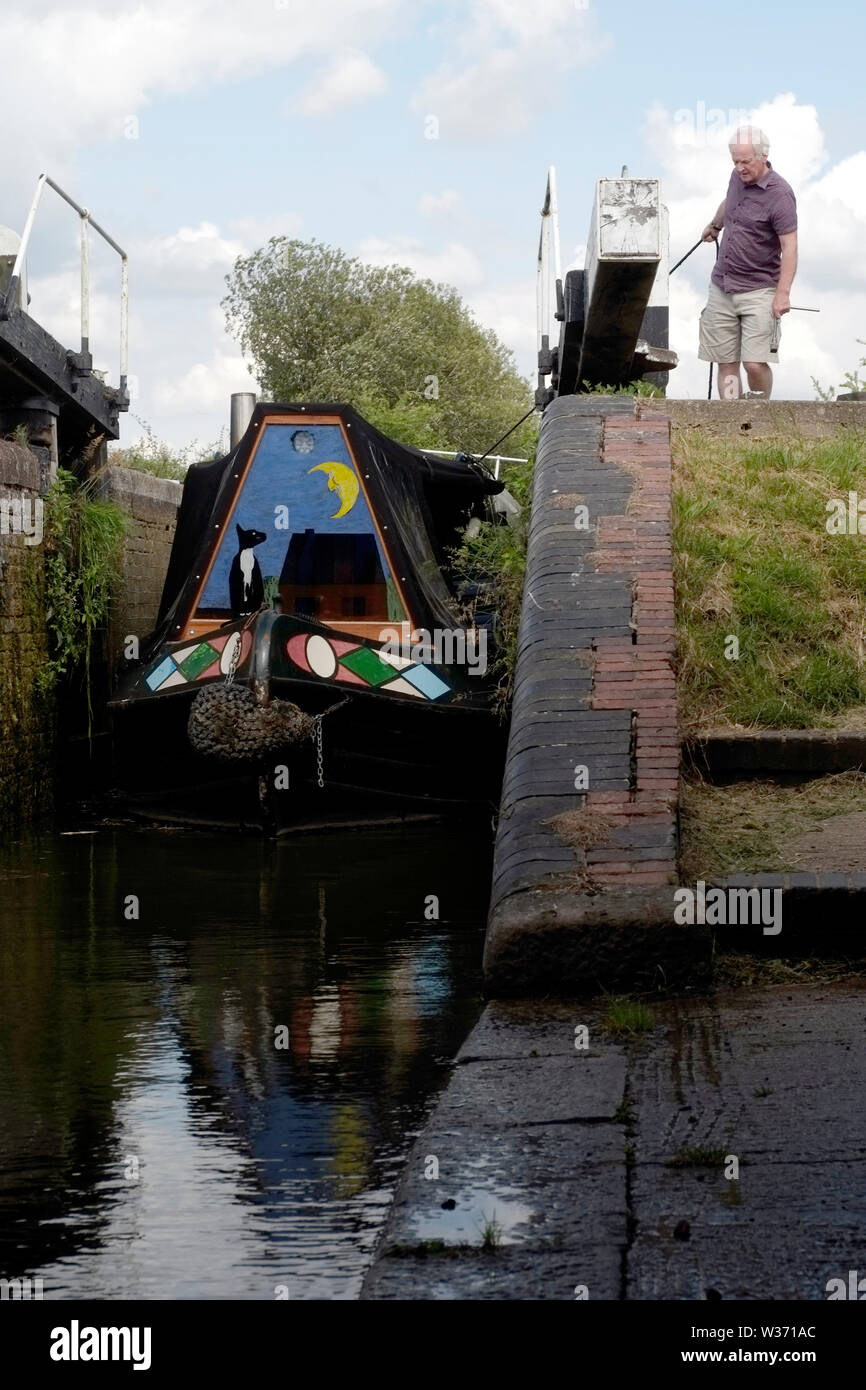 A canal boat owner pulling his narrow boat by rope through a lock after ...