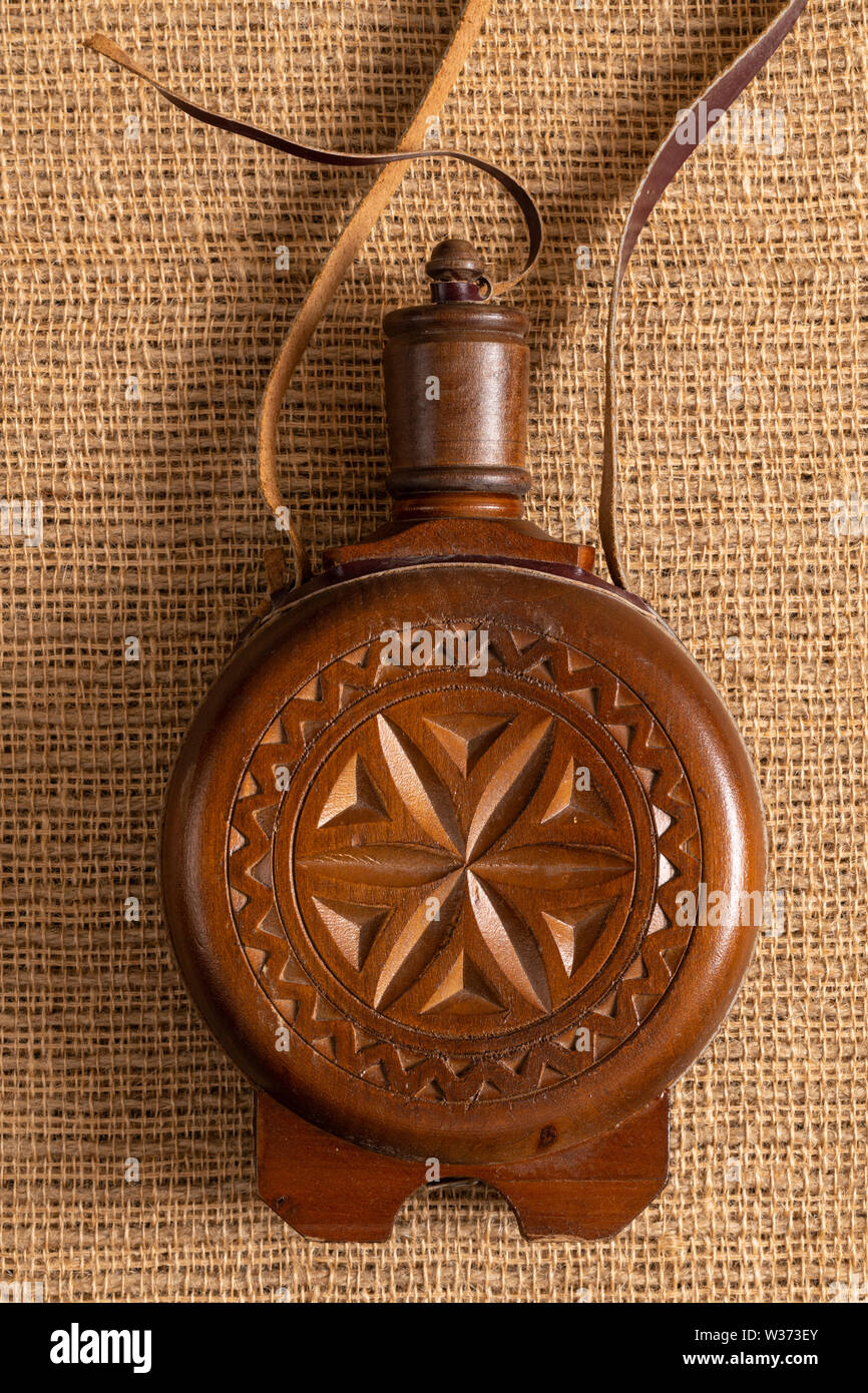 Old traditional flask or bottle container covered in carved wood for
