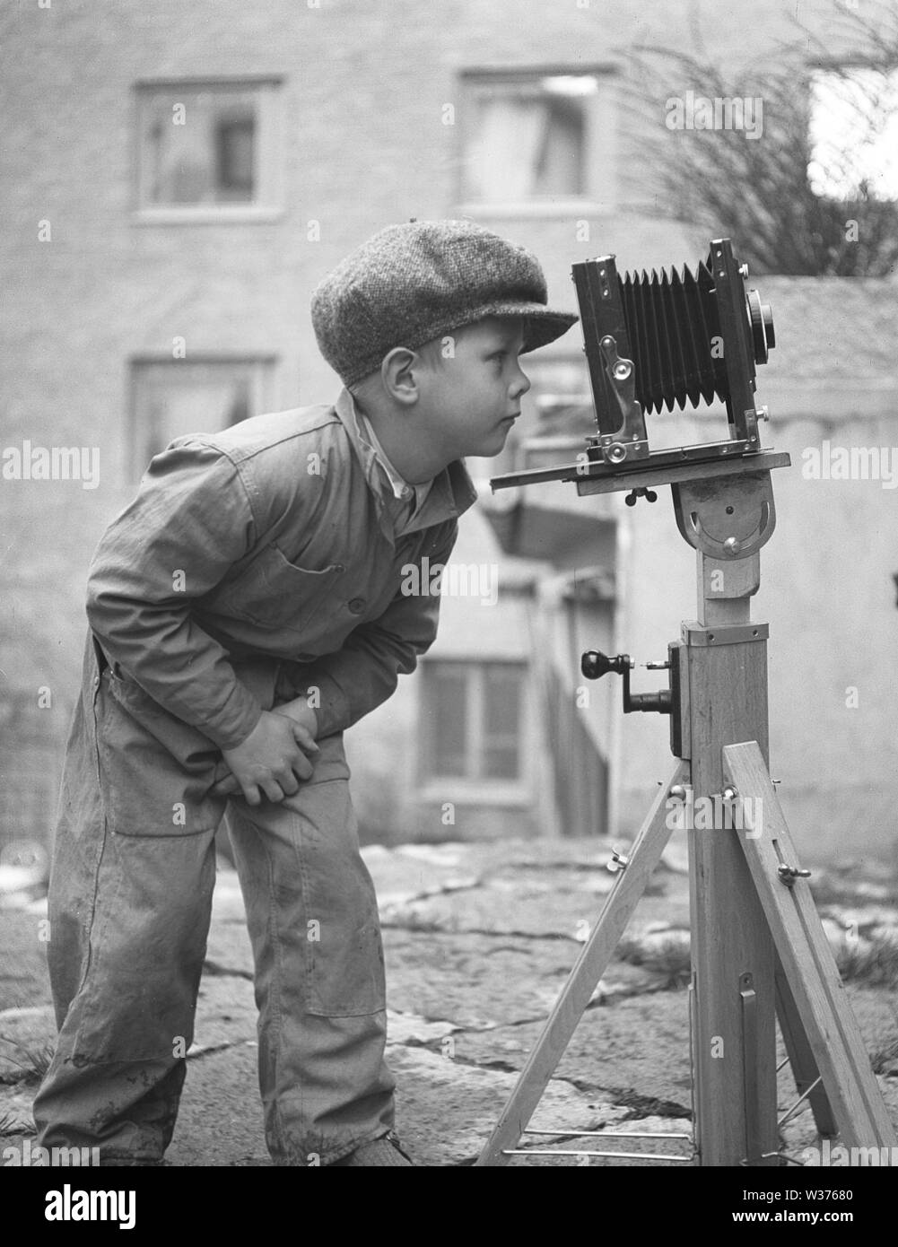 Boy in the 1940s. A curious child is looking into a camera mounted on a tripod.   Sweden 1945. Kristoffersson Ref N107-5 Stock Photo