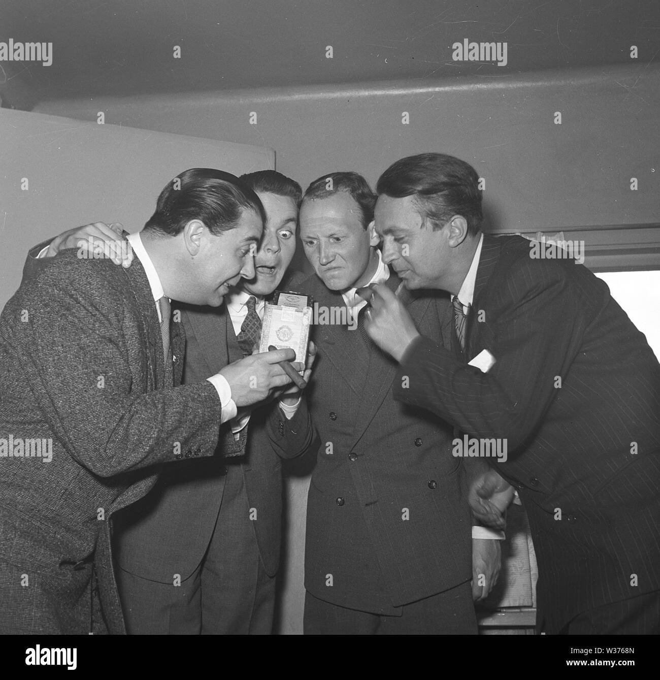 Men in the 1940s. A group of four men looks as if they have different opinions regarding the content of the opened cigar box. Sweden 1945. Kristoffersson P124-2 Stock Photo