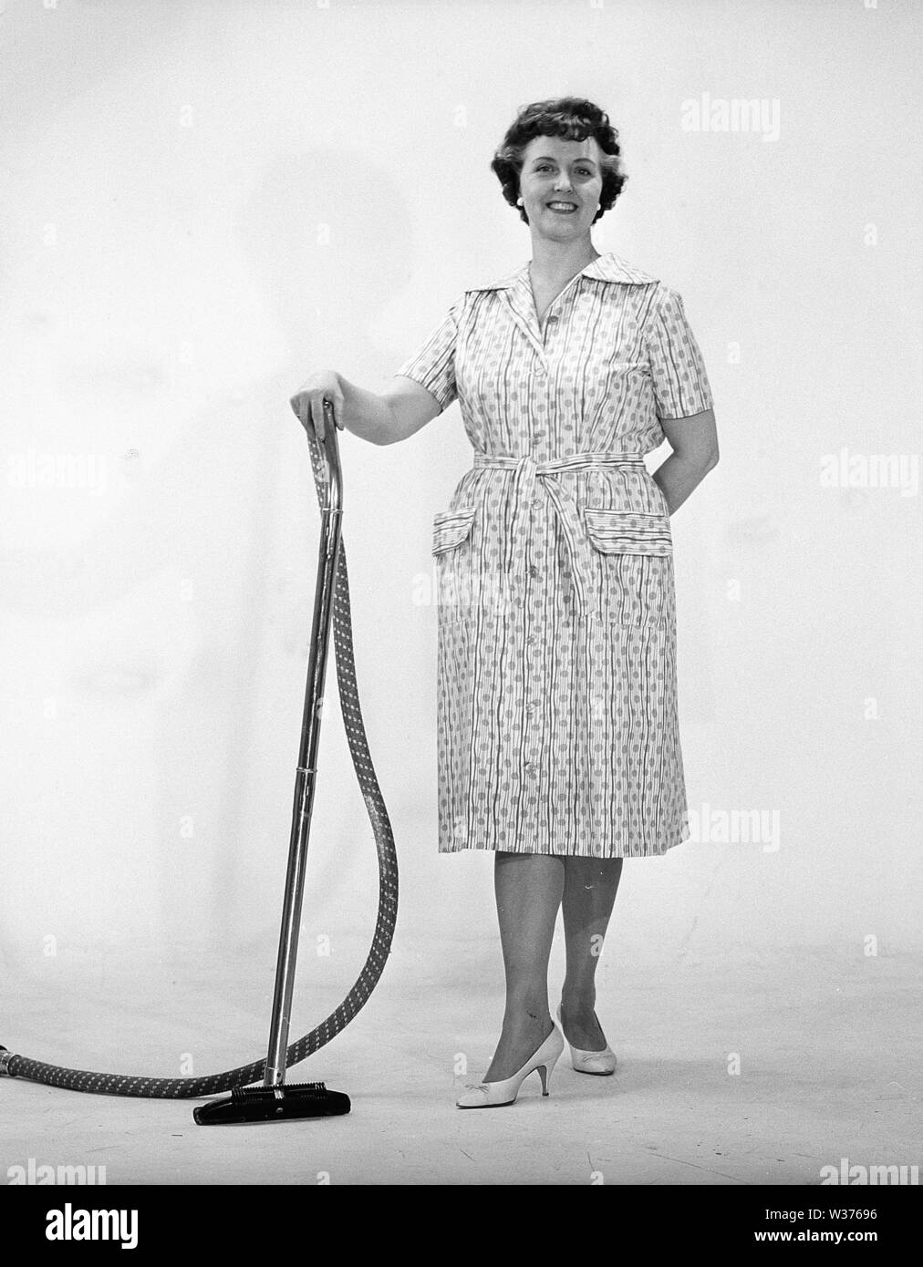 Cleaning day in the 1960s. A woman is standing holding a vacuum cleaner, looking happy. Sweden 1960s Kristoffersson ref CN109-10 Stock Photo
