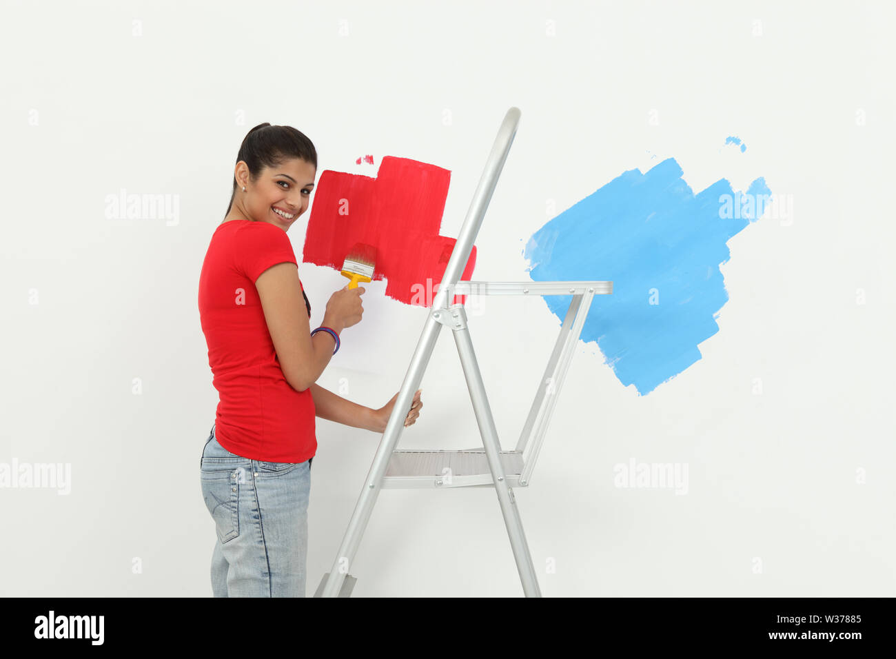 Woman painting a wall and smiling Stock Photo - Alamy