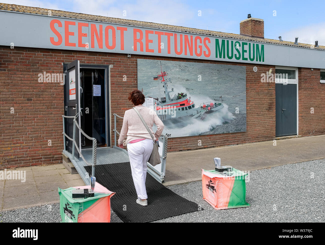 26 June 2019, Schleswig-Holstein, Fehmarn: A woman enters the sea rescue museum in the harbour of Burgstaaken on Fehmarn. Photo: Markus Scholz/dpa Stock Photo