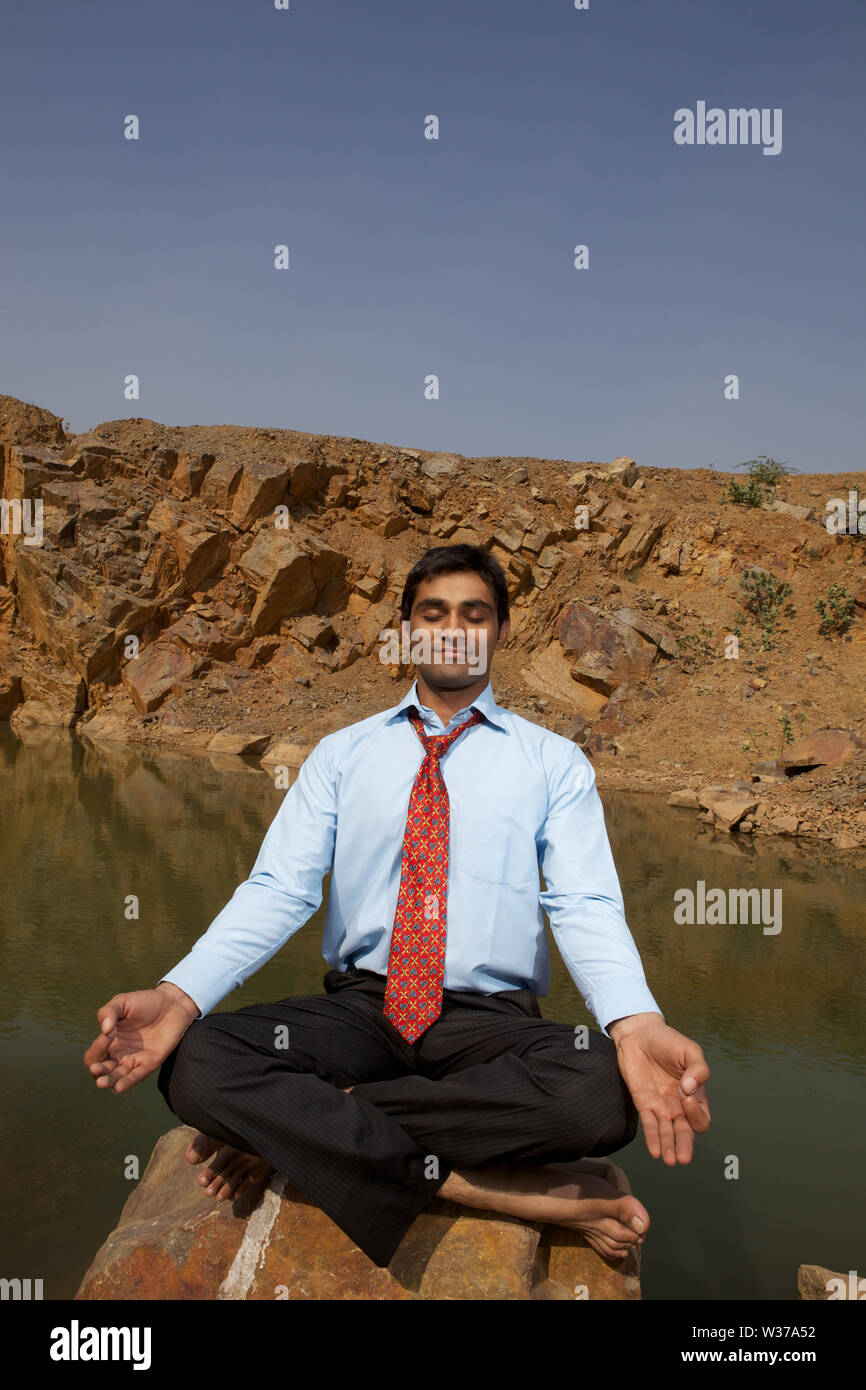 Businessman sitting in yoga pose Stock Photo - Alamy
