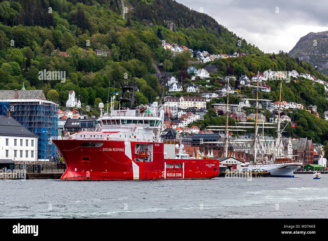 Offshore multi service standby rescue vessel Ocean Response in the port of Bergen, Norway. Tall ship, barque Statsraad Lehmkuhl in background. Stock Photo