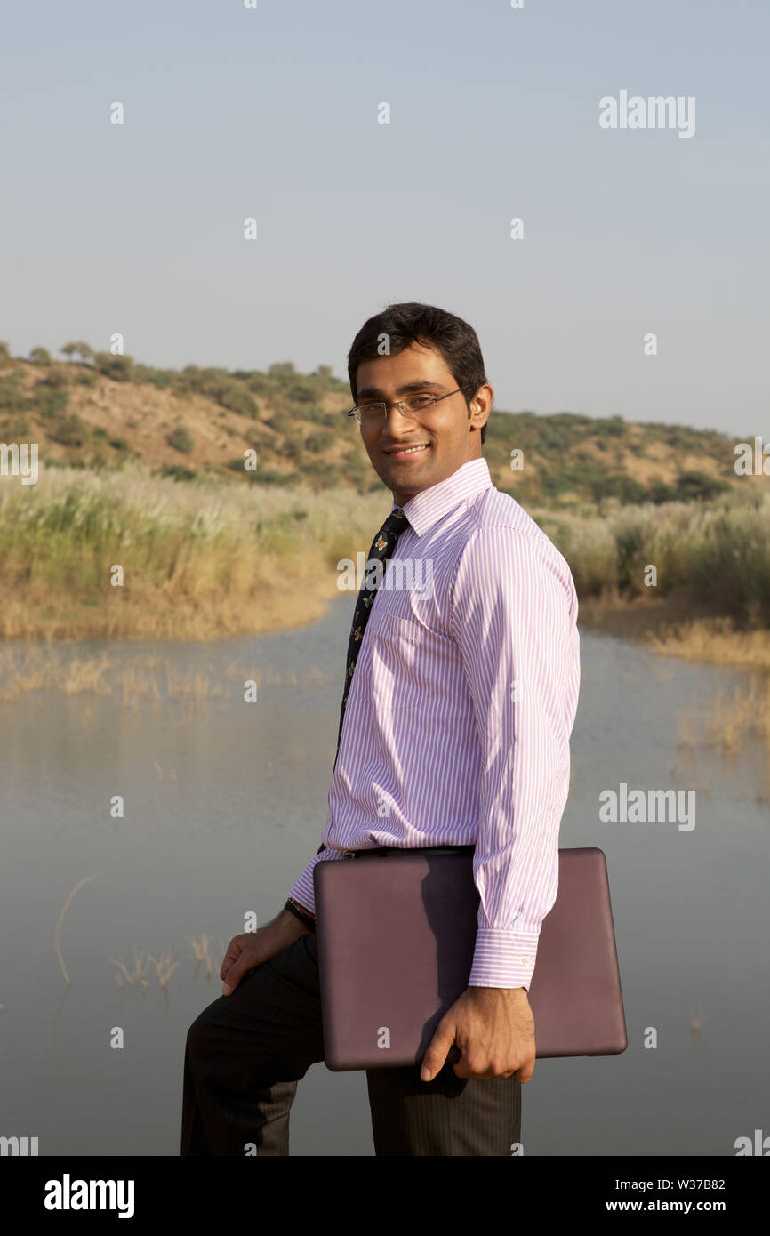 Portrait of a businessman standing by a pond smiling Stock Photo - Alamy