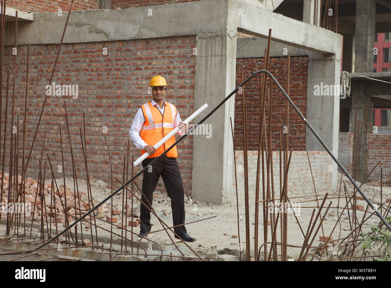 Architect at construction site and holding blueprint Stock Photo - Alamy