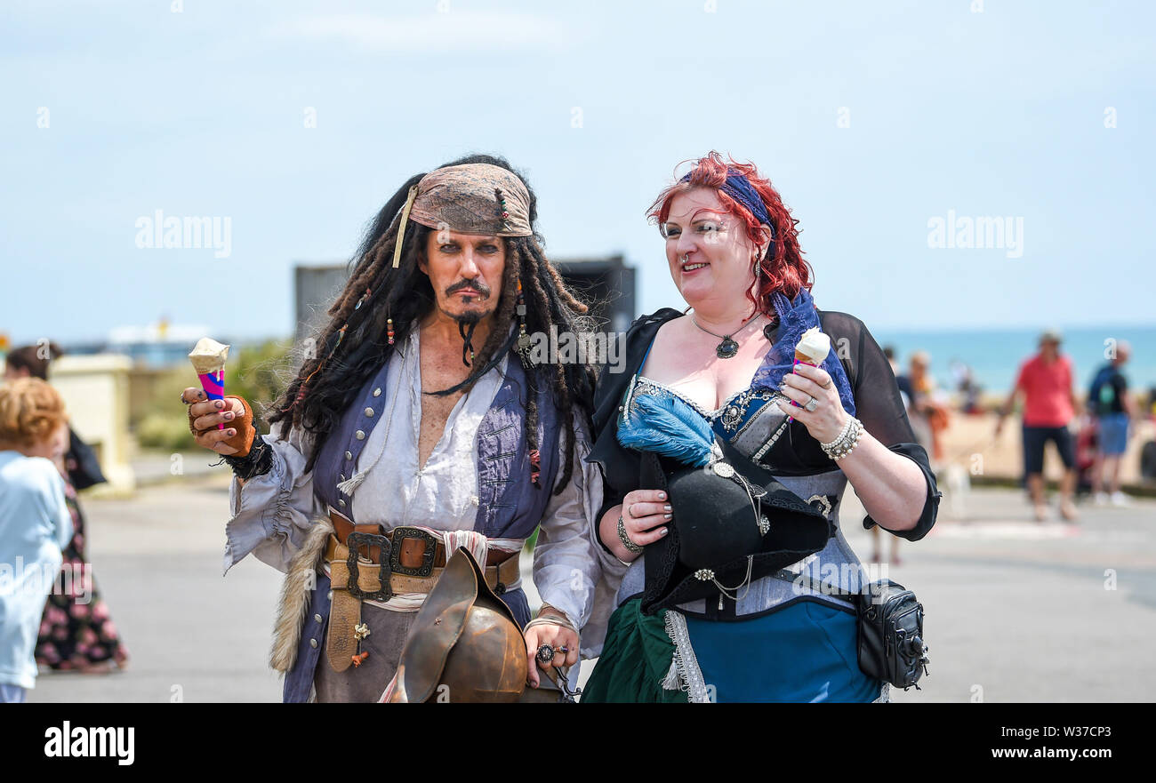 Brighton UK 13th July 2019 -  A Captain Jack Sparrow lookalike gets an ice cream at the March of the Mermaids parade makes its way along Brighton seafront in hot sunny weather today . The March of the Mermaids parade in Brighton was the first event of its kind in the UK, created in 2012 and inspired by the Coney Island Mermaid Parade in New York and is a celebration of our seas and sea life, raising awareness of marine conservation issues  . Credit : Simon Dack / Alamy Live News Stock Photo