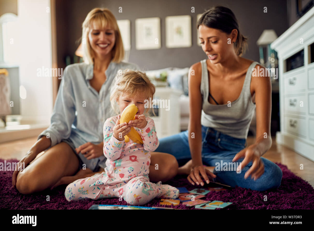 Cute female little child peels banana inside Stock Photo