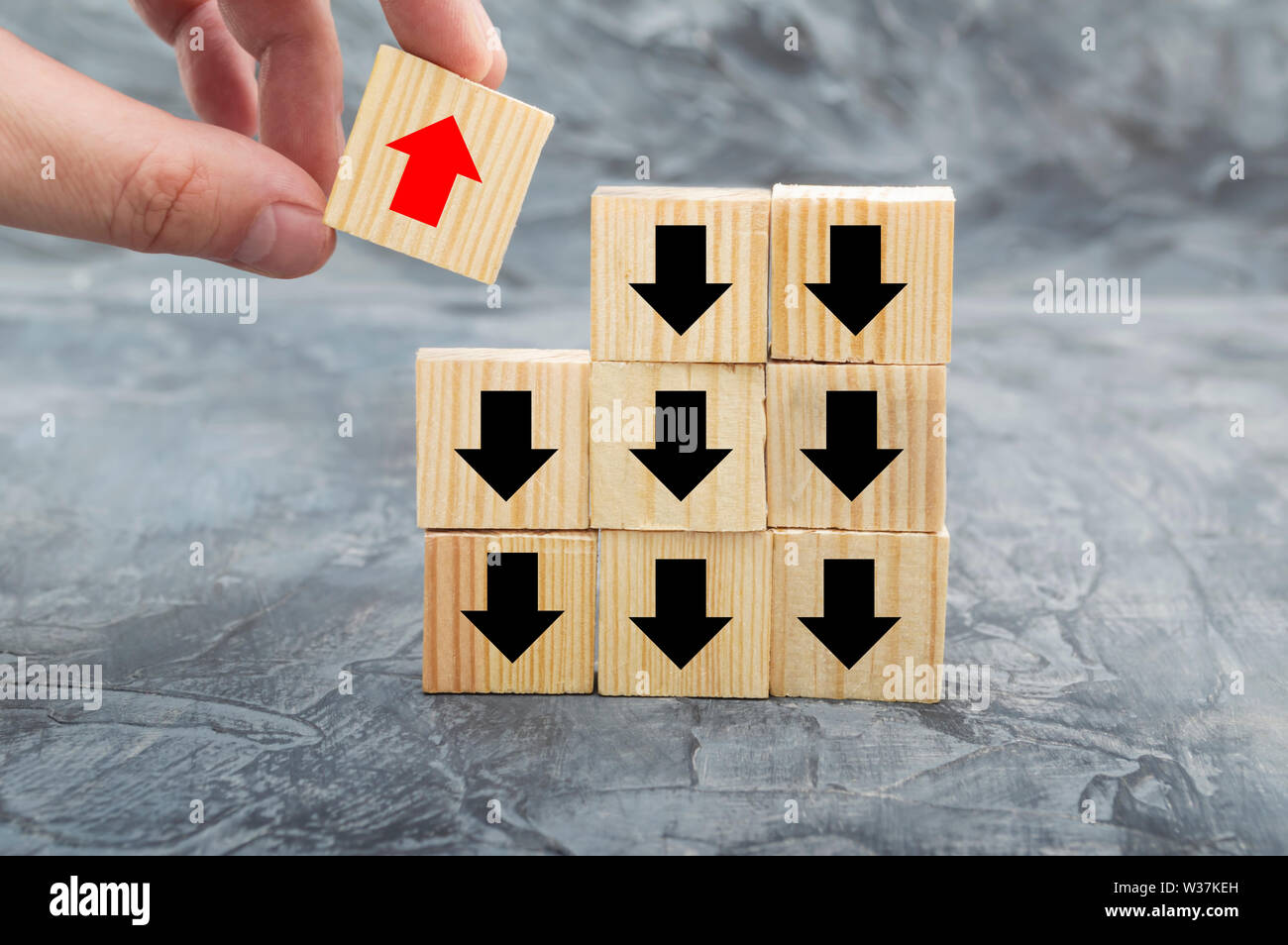 Hand picked red wooden block arrow facing the opposite direction black arrows. Concept with different people. Going for success, technology innovation Stock Photo