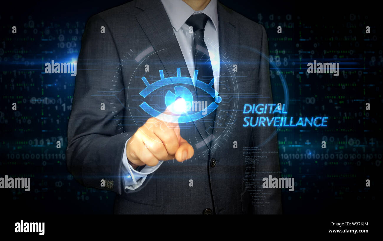 A businessman in a suit and screen with cyber eye hologram. Man using hand on virtual display interface. Digital surveillance, spying, hacking and vio Stock Photo