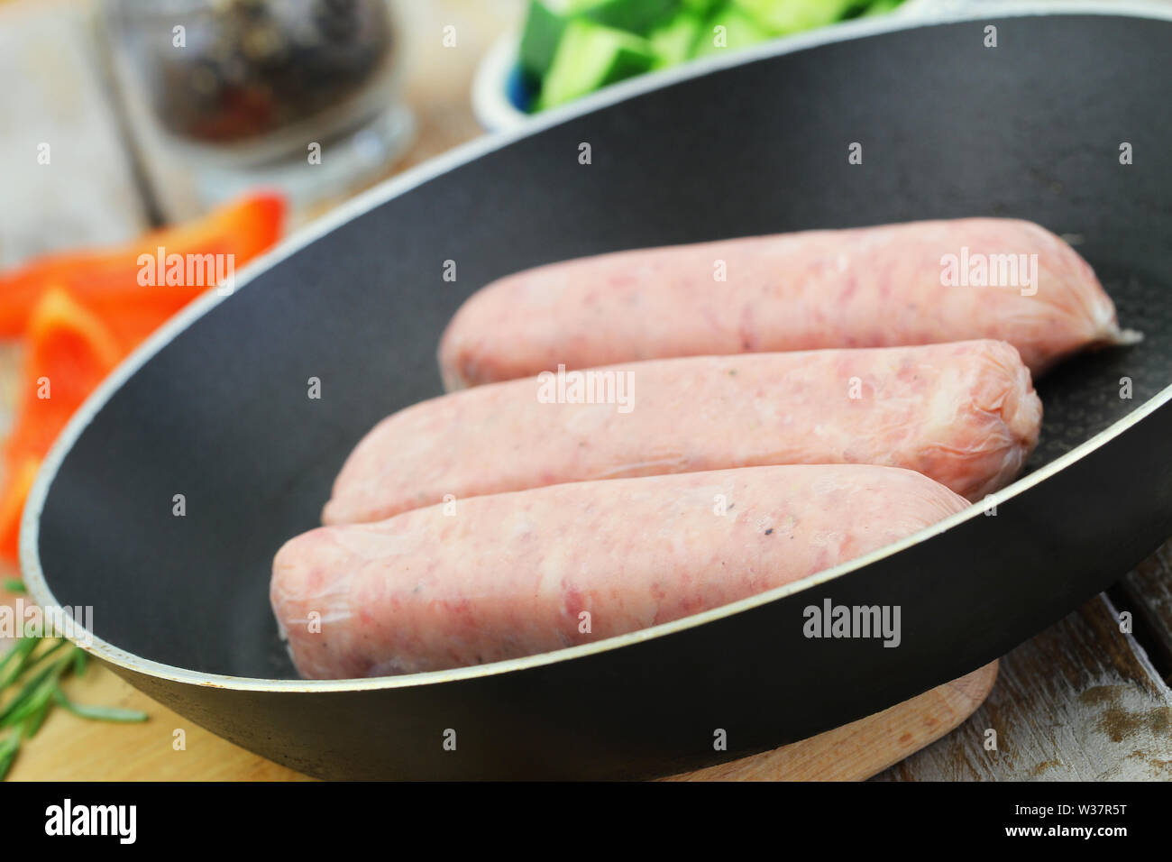Uncooked British pork sausages in frying pan Stock Photo
