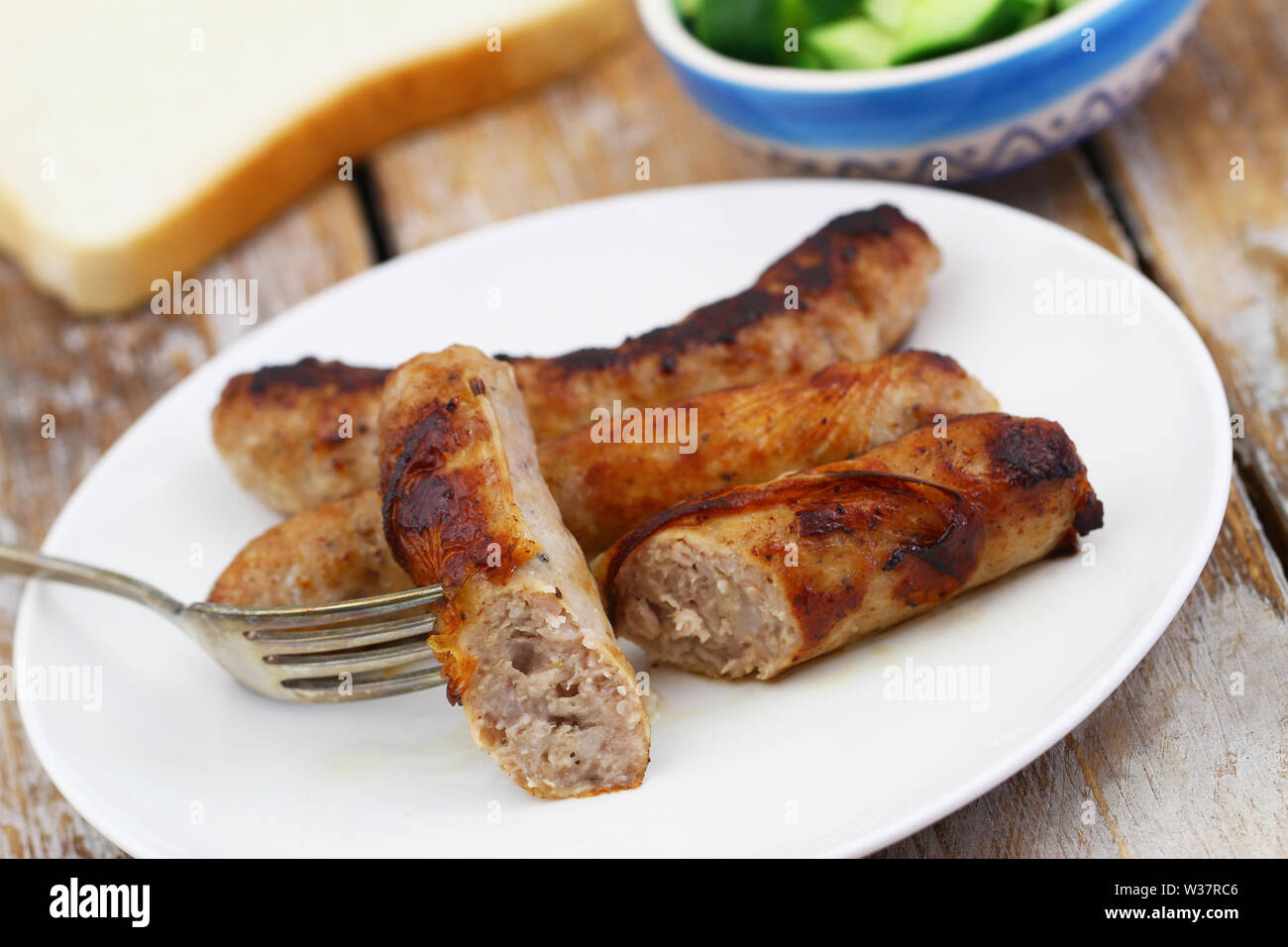Crispy, tasty fried British sausage on fork, closeup Stock Photo