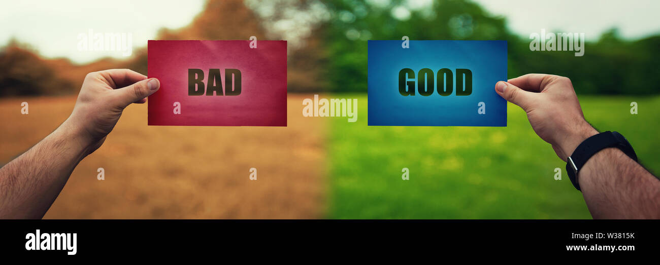 Man hands holding two colored paper sheets with opposite text good and