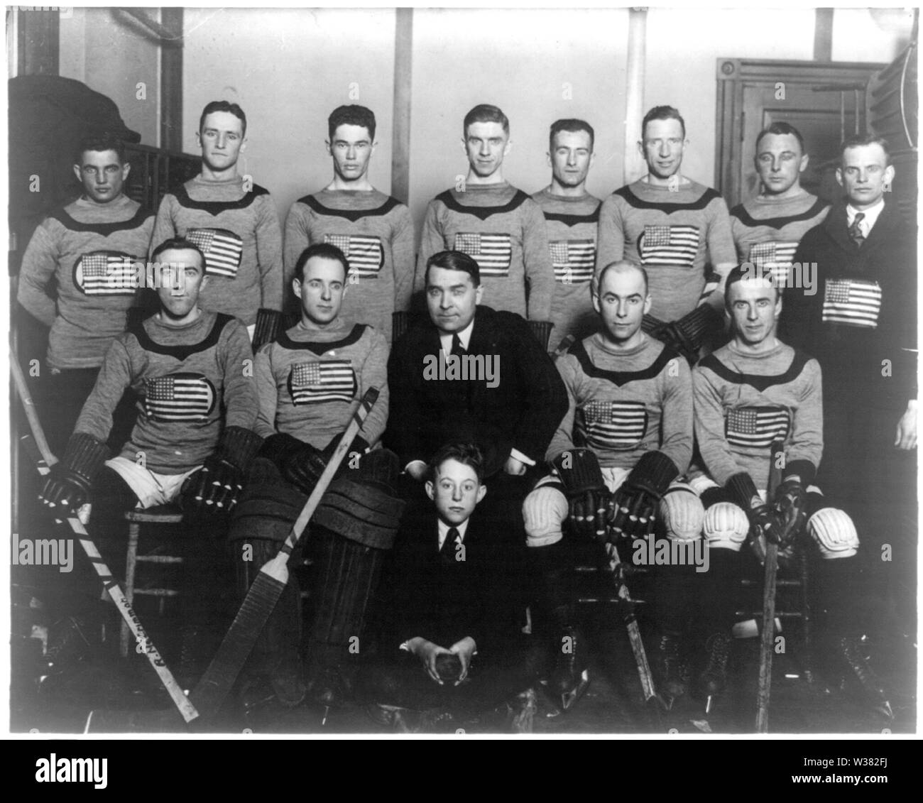 1920 USA Men's Olympic ice hockey team.  Left to right, standing: Cyril Weidenborner, Anthony Conroy, George Geran, Joe McCormick, Frank Goheen, Ed Fitzgerald, Leon Tuck, unknown.  Left to right, sitting: Frank Synott, Raymond Bonney, unknown, Herb Drury, Larry McCormick.  Unknown child sitting on floor. Stock Photo