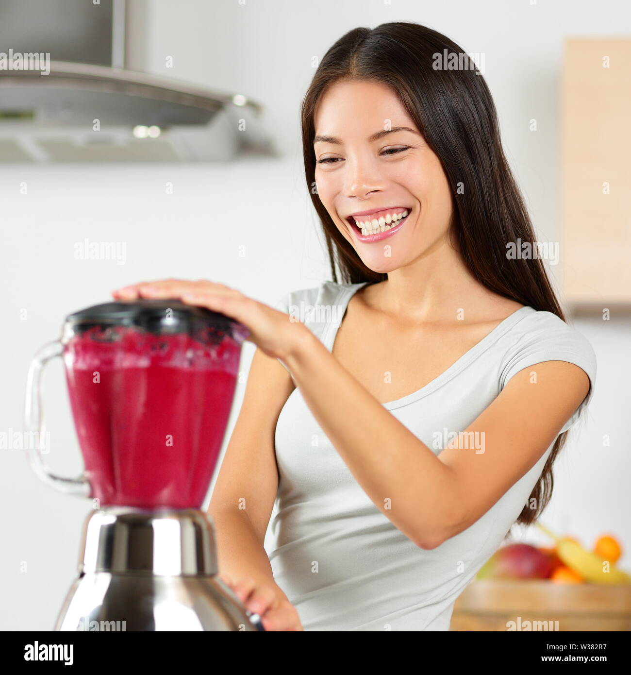 Smoothie woman blending healthy beet - fruit juice. Asian young adult using home appliance kitchen blender to make vegan organic vegetable smoothie using raw ingredients for diet. Stock Photo