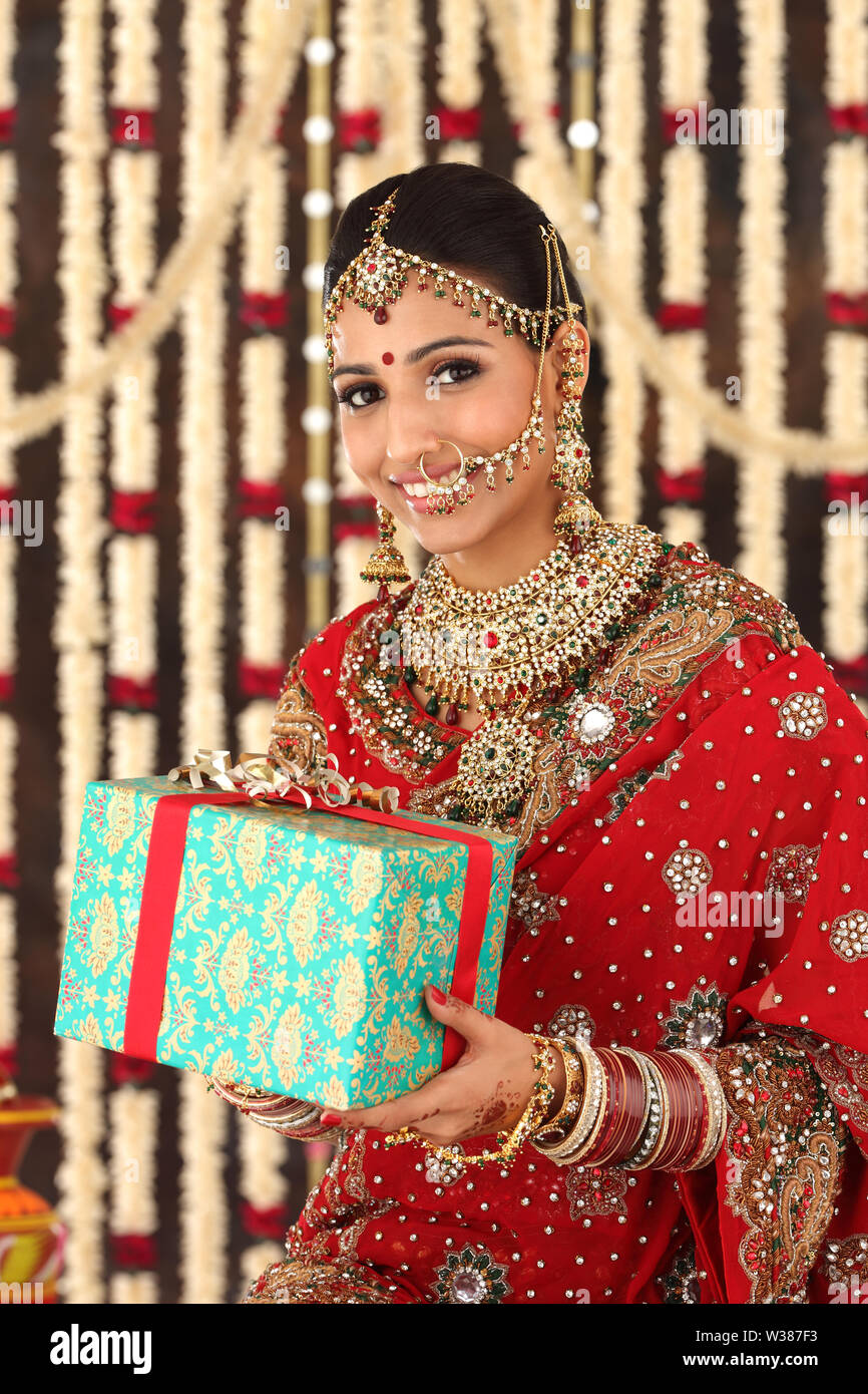 Portrait of an Indian bride holding gift box and smiling Stock Photo