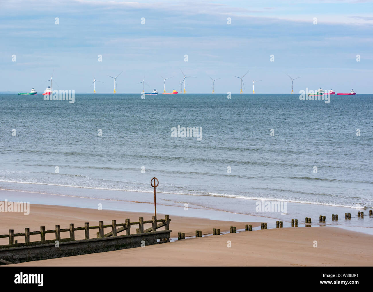 Offshore supply ships anchored by wind turbines in offshore windfarm, Aberdeen beach with groyne, Scotland, UK Stock Photo