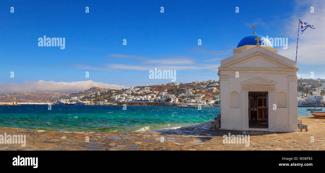 Whitewashed and blue domed Agios Nikolaos church in Mykonos, Greece, Europe. Panoramic view of old town and harbor: traditional greek village. Stock Photo