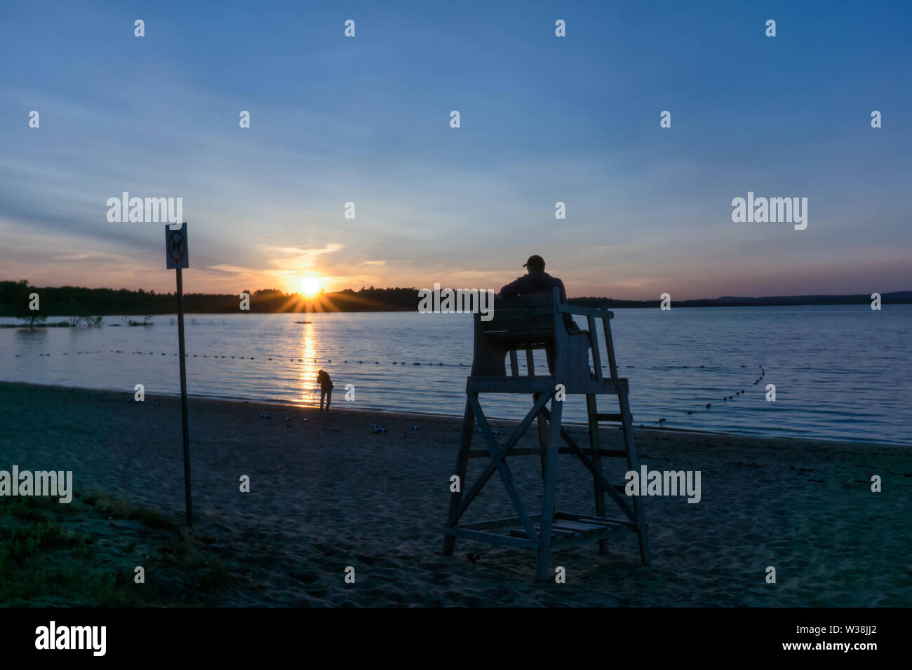 Canada, Petawawa, sunset at Black Bear Beach, a man is sitting in the rescue tower, watching another man taking photos from sunset Stock Photo