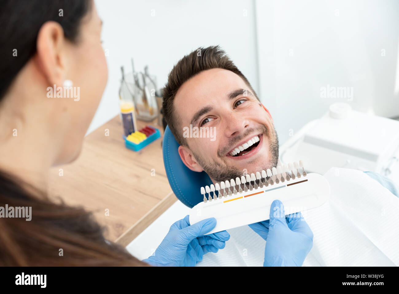 Handsome young man in stomatology clinic with female dentist. Healthy teeth whitening. Stock Photo