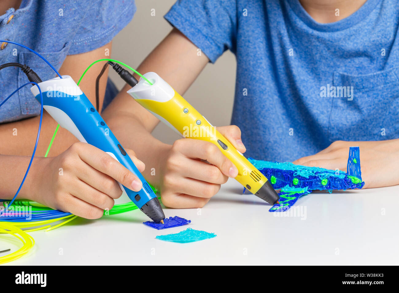 Two kid hands creating with 3d printing pens Stock Photo - Alamy