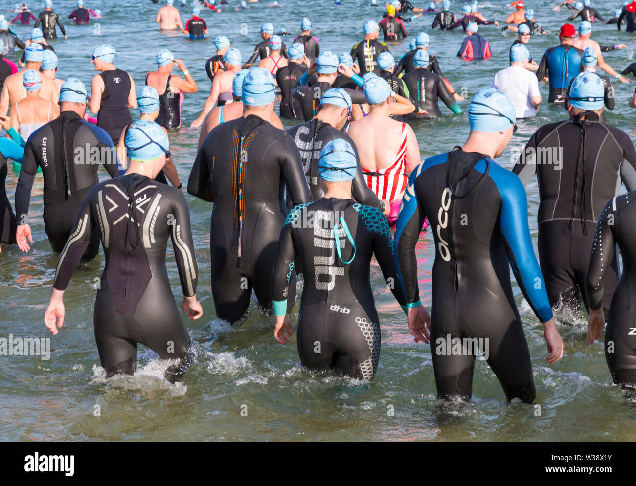 Bournemouth, Dorset UK. 13th July 2019. Pier to Pier sunset swim where swimmers brave the English Channel swimming from Bournemouth to Boscombe piers in 1.4 mile open water challenge, raising funds for BHF, British Heart Foundation. The inaugural sunset swim at Bournemouth where swimmers have 2 hours to complete the swim then relax on the beach to enjoy the sunset, ahead of two more Pier to Pier swims taking place tomorrow during the day – thousands take part in the three swims. A lovely warm sunny evening for the swim. Credit: Carolyn Jenkins/Alamy Live News Stock Photo