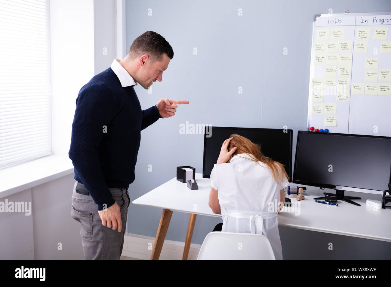 Angry Businessman Shouting At Female Executive In Office Stock Photo