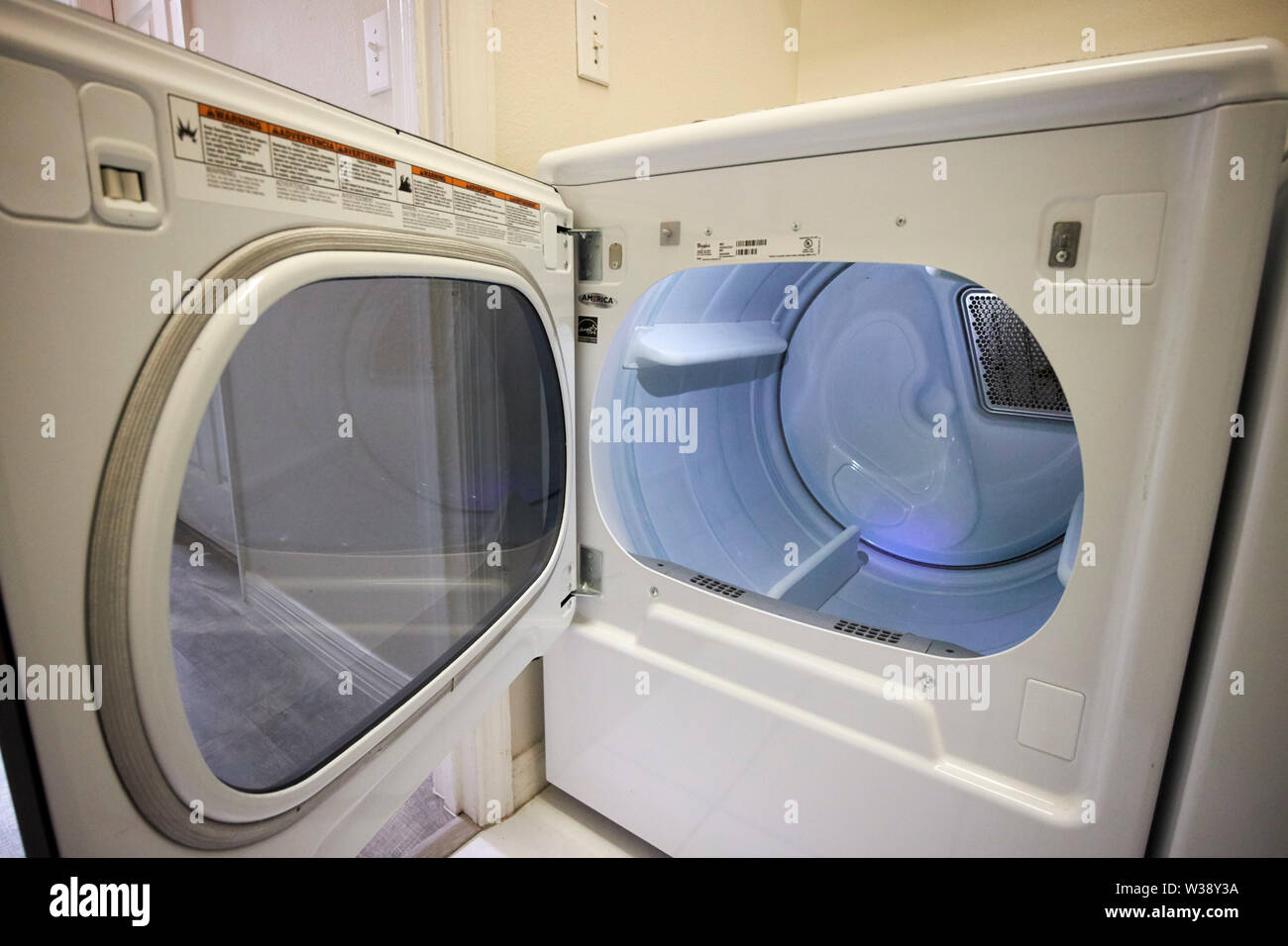 open door and empty drum of a tumble dryer in the laundry room of a home in the USA United States of America Stock Photo