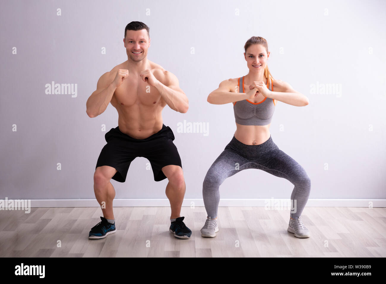 Side View Of Happy Fitness Couple In Sportswear Doing Squat Exercises At  Gym Stock Photo - Alamy