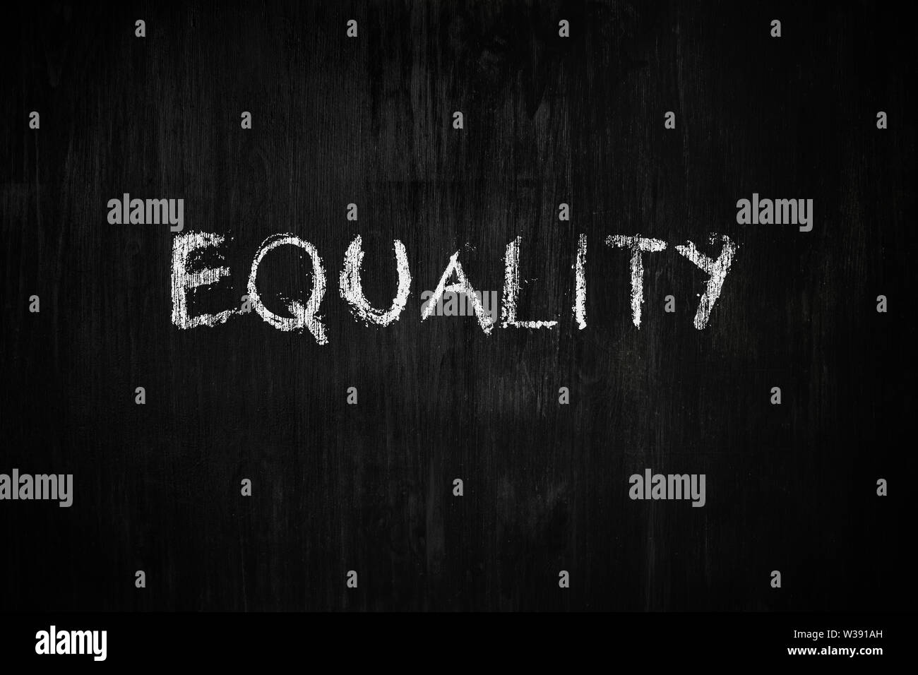 Equality word handwritten on black wood background. Sign, concept of dealing with  social issues - the word 'equality' on a blackboard Stock Photo