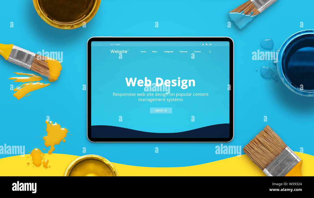 Web design concept with modern flat design theme on a thin tablet surrounded by color brushes and boxes. Top view, flat lay. Stock Photo