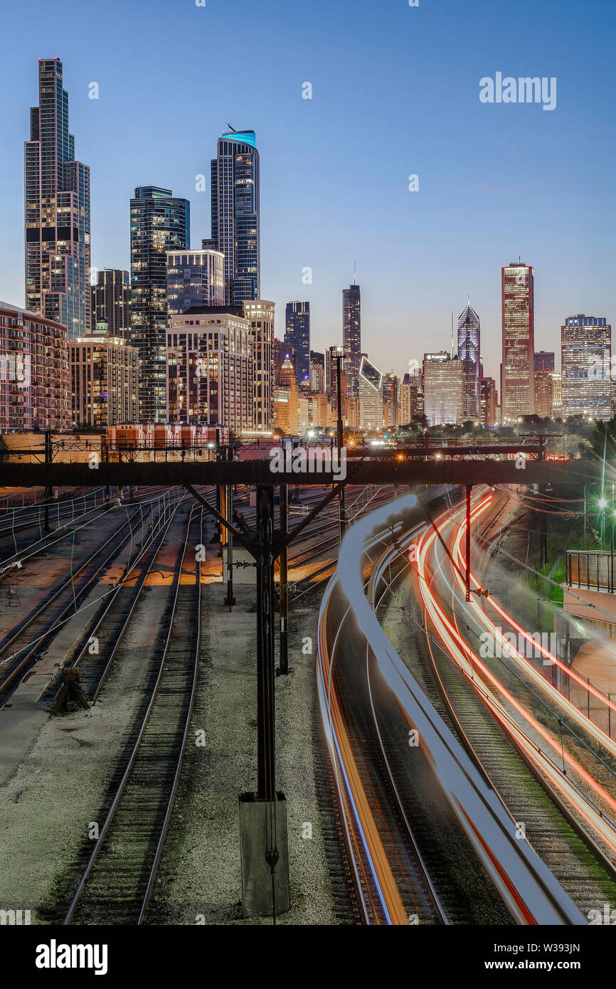 Commuter trains light up the tracks near Soldier Field below the beautiful skyline of downtown Chicago, Illinois, on a clear summer night. Stock Photo