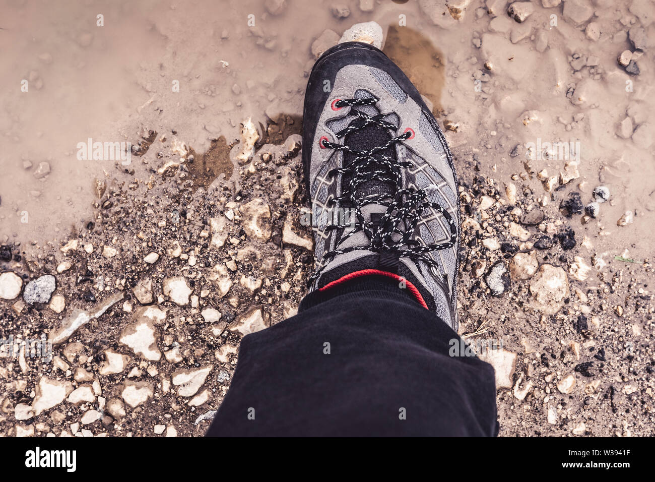 Male Leg Wearing Sportive Hiking Sneakers Shoes in Mud and Water