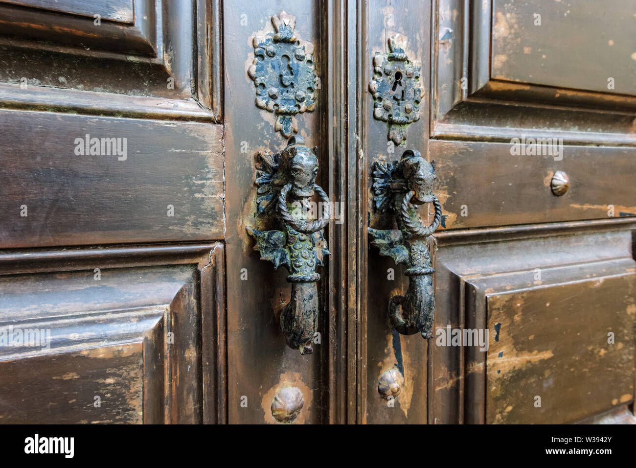 Seahorse shaped door handles on old brown wooden door in Lisbon, Portugal Stock Photo