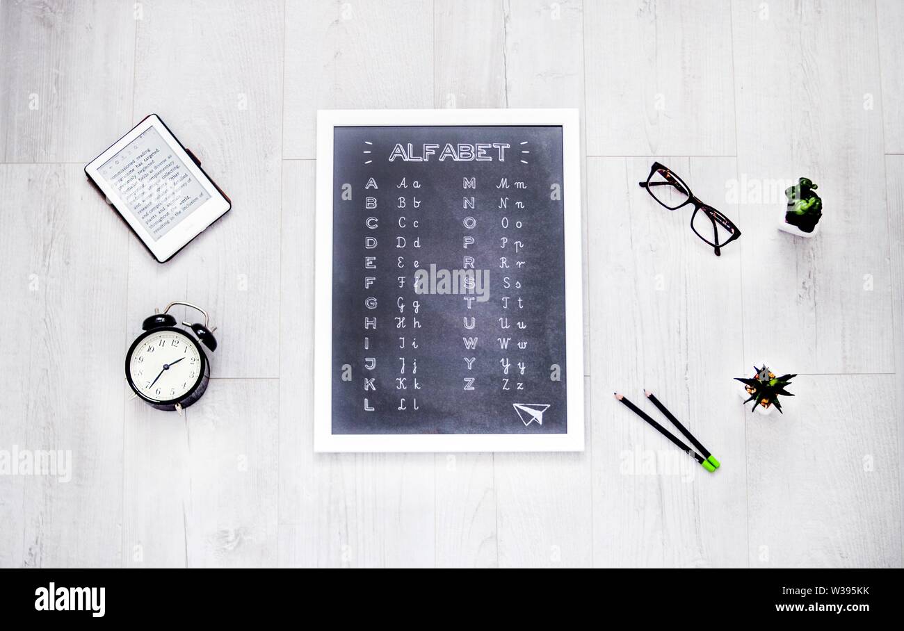 Overhead shot of a small whiteboard with alphabet letters on it on a white wooden background Stock Photo