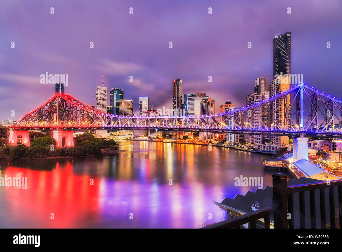 Brightly illuminated Story bridge over Brisbane river in Brisbane city CBD before sunrise when urban lights reflect in still waters. Stock Photo